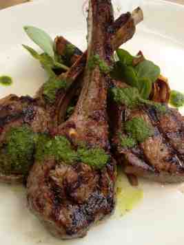 Summer rooftop dining: lamb chops on roasted artichokes with pesto sauce.
